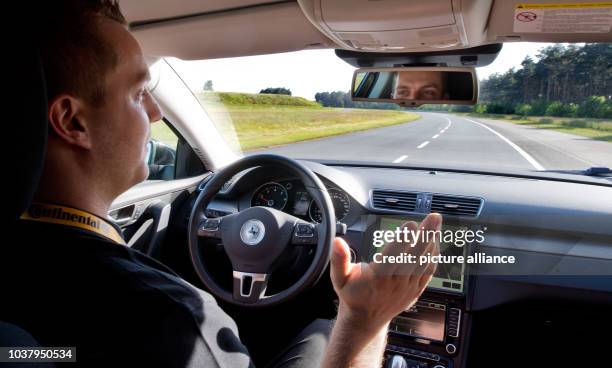 Test driver sits in a test car from automotive parts manufacturer Continental that can partially be driven with Autopilot on the test track...