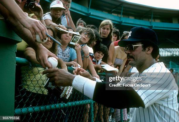 Outfielder Reggie Jackson of the New York Yankees signs autographs for fans during a spring training Major League baseball game circa 1980 in Tampa,...