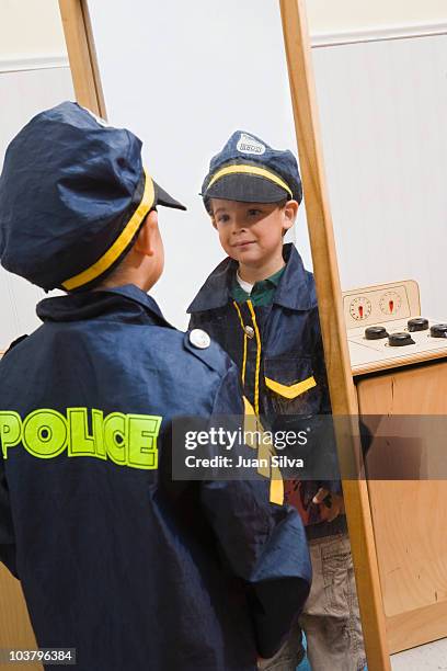 boy with police costume looking himself at mirror - uniforme della polizia foto e immagini stock