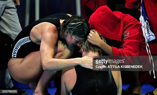 Hungarian players, Orsolya Takacs and Orsolya Kaso comfort their teammate goalkeeper Aniko Gyongyossy as they lost a group match of the water polo...