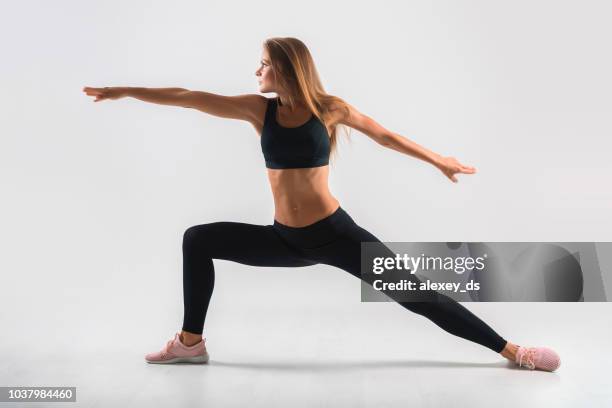 femme en vêtements de sport qui s’étend de ses muscles de la jambe. studio shot - gymnaste photos et images de collection