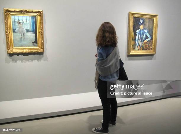 Visitor stands before the paintings "Dancer in the artists studio" of Edgar Degas and "Lady in Blue" of Paul Cezanne in the exhibition "Icons of...