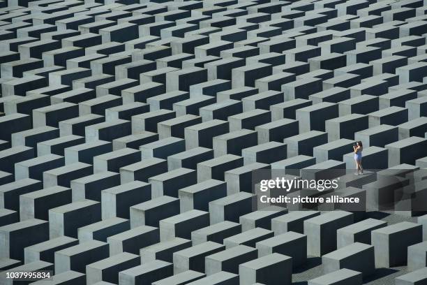 Visitor takes a picture as she stands on one of the steles at the Memorial to the Murdered Jews of Europe, also known as the Holocaust Memorial,...