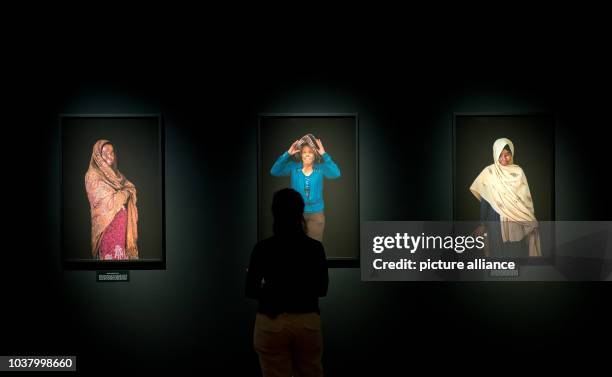 Visitor views pictures by photographer Ann-Christine Woehrl are on display at the exhibition 'UN/SICHTBAR - Women survive Acid' in Munich, Germany,...