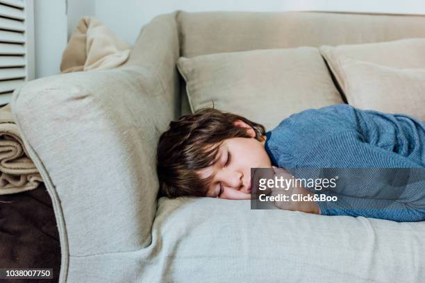 nine years old boy sleeping on a sofa (home interior) - 8 9 years stock pictures, royalty-free photos & images