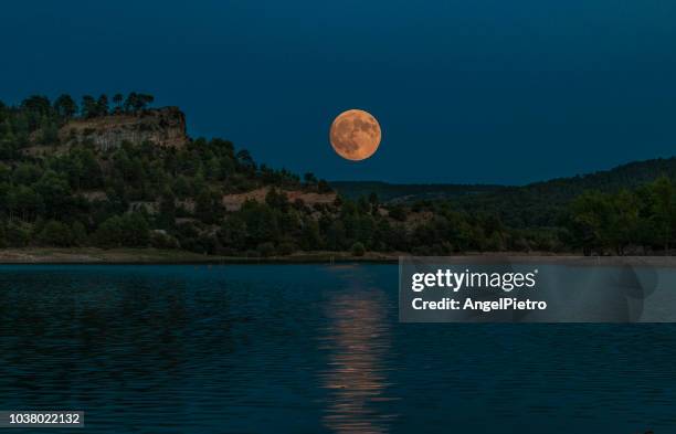 luna llena sobre la laguna y entre las montañas - gebirgskamm stock-fotos und bilder