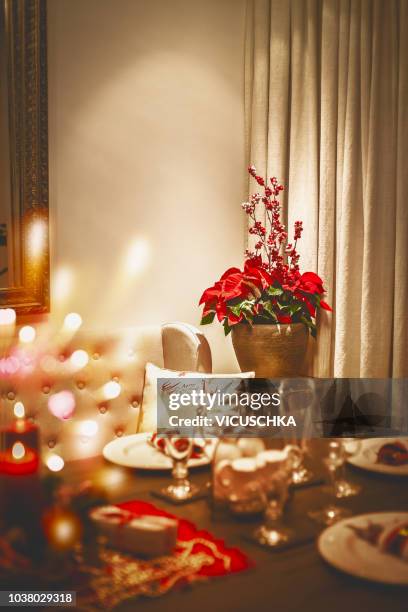 cozy christmas home. covered and decorated holiday table with poinsettia and festive bokeh lighting - weihnachtsstern stock-fotos und bilder