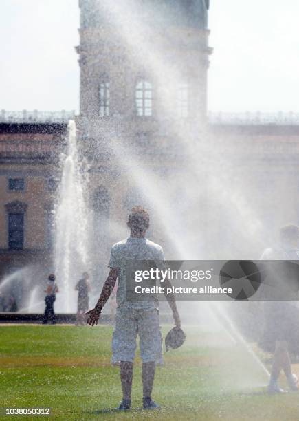 Young man runs through the sprinkler syster in the 30 degree temperatures at Schlosspark Charlottenburg in Berlin, Germany, 26 July 2013. Photo:...