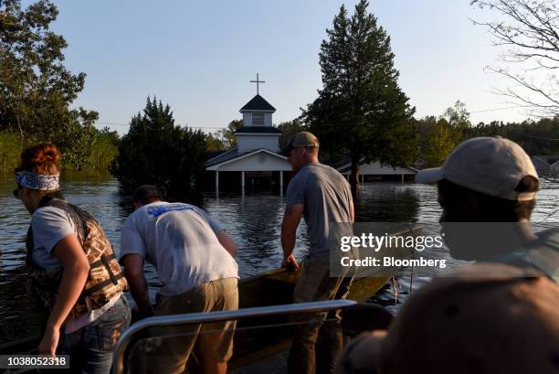 Members of a volunteer search and rescue team ride a boat to deliver care to animals stranded in floodwater after Hurricane Florence hit in Bergaw,...