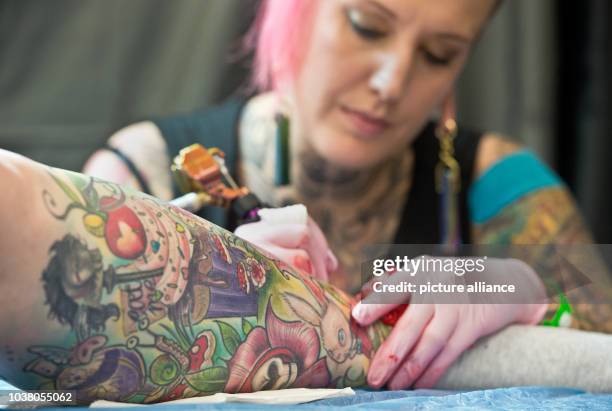 Young woman adds to her already heavily-tattooed lower leg at the International Tattoo Convention in Frankfurt am Main, Germany, 21 March 2015....