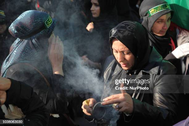 An Iranian woman carries incense to bless participants as Iranian Shiite Muslim mourners take part in a Muharram procession in Toronto, Ontario,...