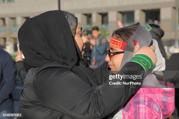 Woman adjusts a religious headband on her daughter as Iranian Shiite Muslim mourners take part in a Muharram procession in Toronto, Ontario, Canada,...