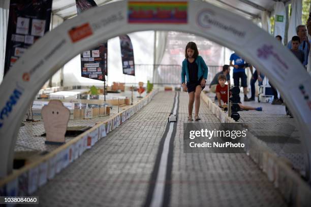 Girl foolows her robot along the track. A robots race took place in Toulouse. Machines are either cars or walking robots. They were supposed to run a...