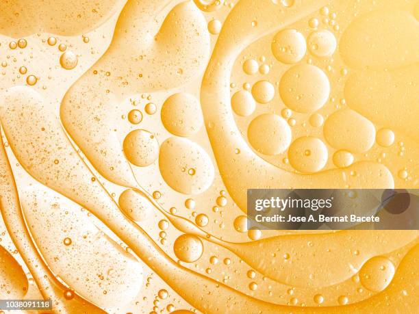 full frame of abstract shapes and textures, formed of bubbles and drops on a orange and yellow liquid background. - brasses photos et images de collection