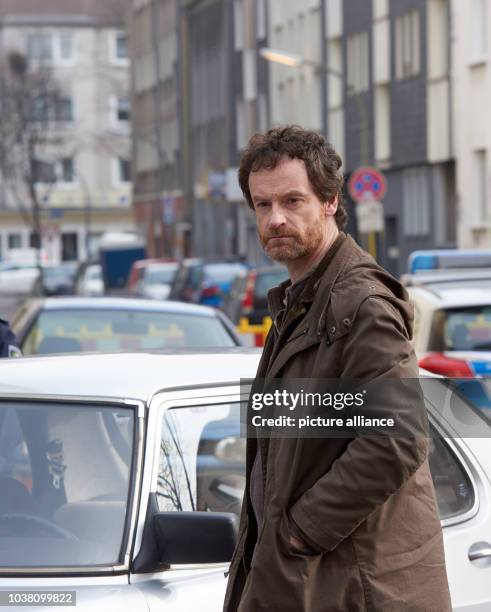 Actor Joerg Hartmann as inspector Faber stands next to a vehicle during a break as the episode 'Zahltag' of the German television series Tatort is...