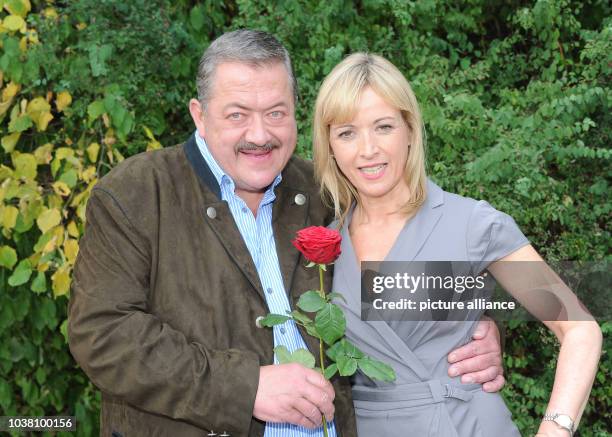 Actor Joseph Hannesschlaeger carrying a red rose and actress Katharina Abt pose during the filming of television crime series 'Die Rosenheim-Cops' by...