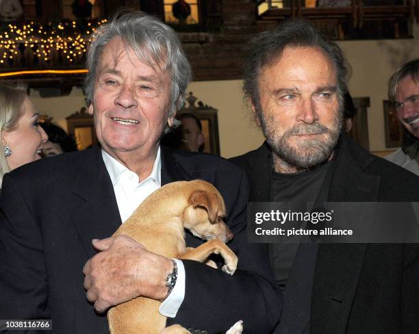 Actors Alain Delon and Franco Nero pose with Molly the dog at a traditional Christmas display at the Gut Aiderbichl animal sanctuary in...