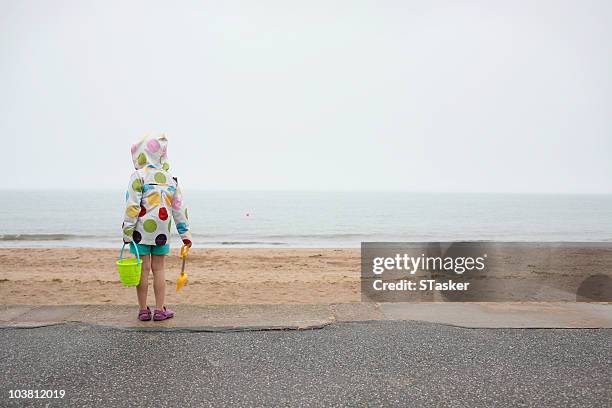 girl in rain on beach - バケツとスコップ ストックフォトと画像