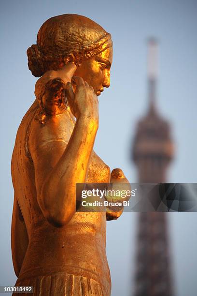 detail of gilded bronze statue on central square of palais de chailot, with top of eiffel tower in background. - bronze statue stock pictures, royalty-free photos & images