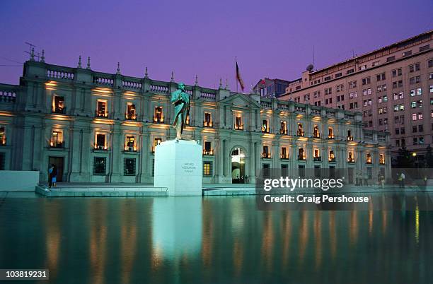 palacio de la moneda and statue of arturo alessandri palma illuminated at dusk. - peace palace stock-fotos und bilder