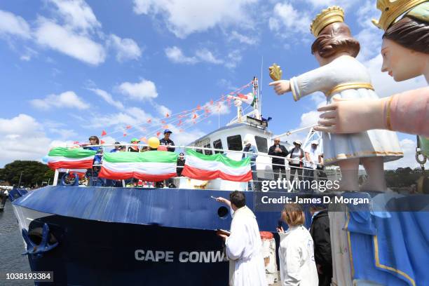 Father Pierluigi Passoni uses an aspergillum to throw water on a fishing vessel during the blessing of the fleet celebrations at Sydney Fish Market...