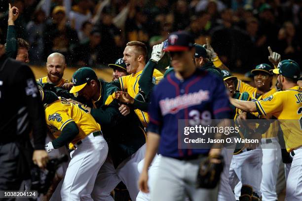 Stephen Piscotty of the Oakland Athletics is congratulated by teammates after scoring on a walk off wild pitch by Trevor Hildenberger of the...