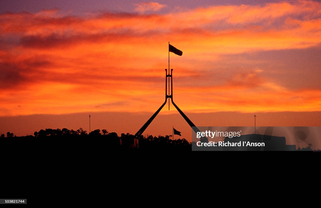 Parliament House flag silhouetted at sunset.