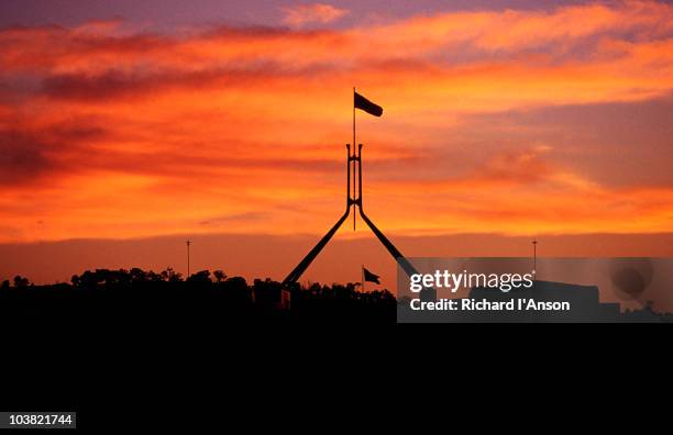 parliament house flag silhouetted at sunset. - australian government stockfoto's en -beelden