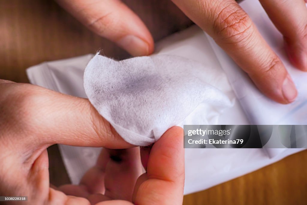 Woman hands taking wet wipe from package.