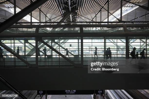 Passengers are silhouetted as they walk across a footbridge at Shenzhen North Railway Station in Shenzhen, China, on Sunday, Sept. 23, 2018. The...