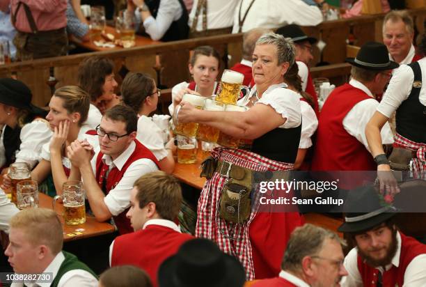 Waitress delivers one liter mugs of beer in the Armbrustschuetzenzelt tent following the Oktoberfest parade of costumes of folk and crafts...