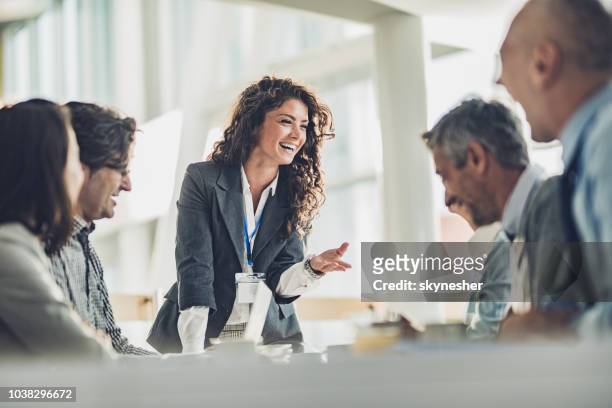 happy female leader talking to her colleagues on a business meeting in the office. - leadership stock pictures, royalty-free photos & images