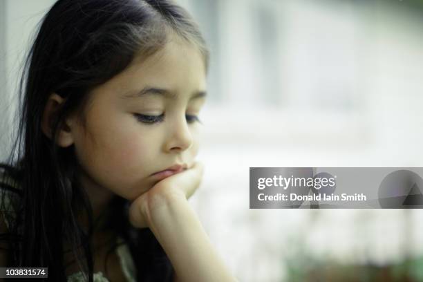 girl by window with chin resting on hand - hand on chin stock pictures, royalty-free photos & images