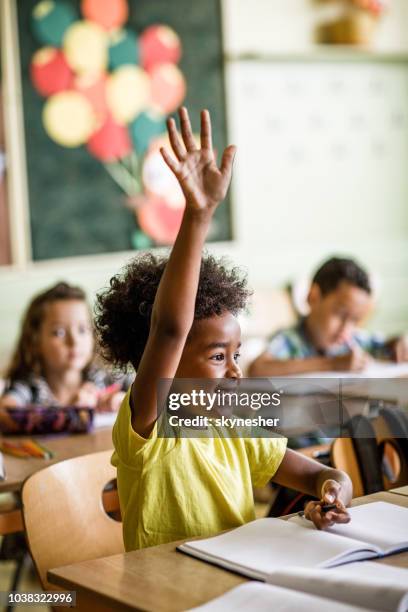 african american elementaire student verhogen haar arm te beantwoorden van de vraag op een klasse. - elementary school classroom stockfoto's en -beelden