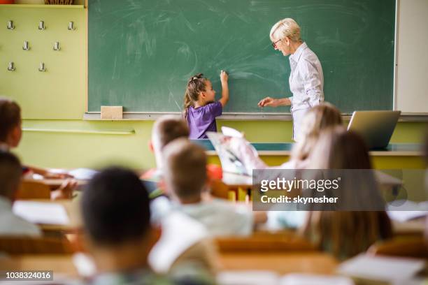 profesor femenino colegiala frente a pizarrón en la escuela primaria de enseñanza. - mature coach fotografías e imágenes de stock