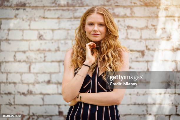 stylish red head girl in front of white brick wall - freckle girl stock pictures, royalty-free photos & images