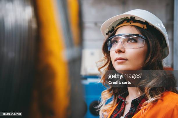 retrato de mujer joven hermosa ingeniero trabajando en el edificio de la fábrica. - carrera fotografías e imágenes de stock