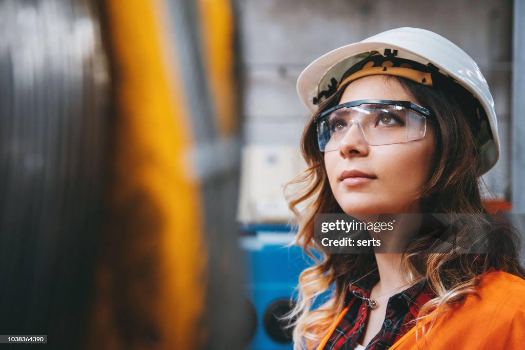 Portret van jonge mooie ingenieur vrouw die werkt in fabrieksgebouw.