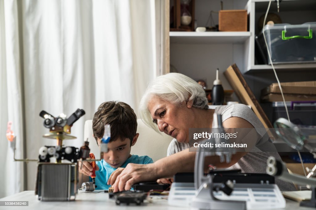 Little Boy And Grandmother Building Robot