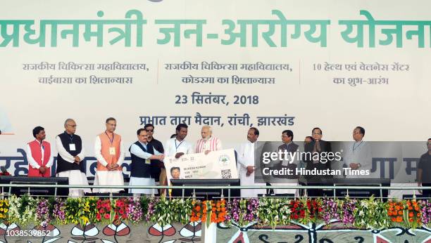 Prime Minister Narendra Modi gives a health card to beneficiaries as he launches Ayushman Bharat-National Health Protection Scheme, at Prabhat Tara...