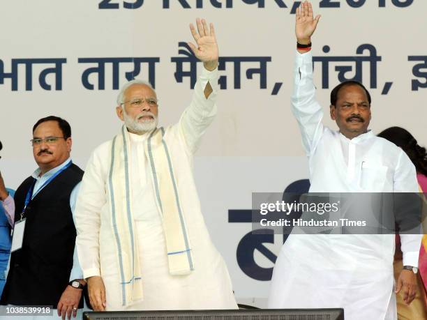 Prime Minister Narendra Modi and Jharkhand chief minister Raghubar Das waves to supporters as Health Minister Jagat Prakash Nadda looks on during the...