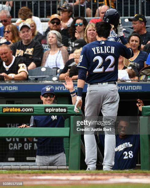 Christian Yelich of the Milwaukee Brewers is greeted in the dugout by manager Craig Counsell after coming around to score after Mike Moustakas was...