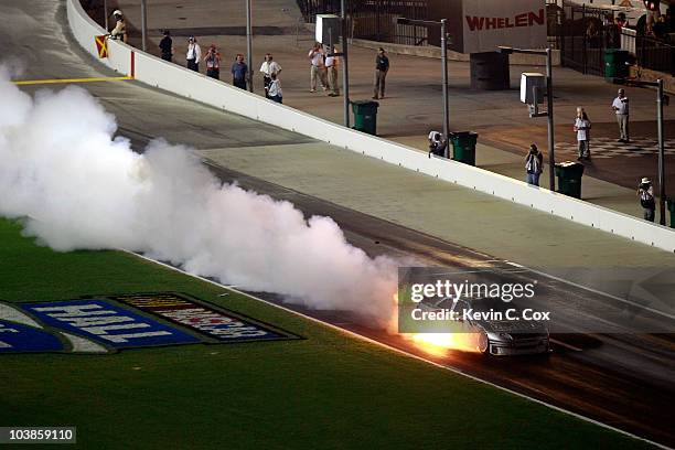 Scott Speed drives the Red Bull Toyota down pit road as it catches fire after an incident in the NASCAR Sprint Cup Series Emory Healthcare 500 at...