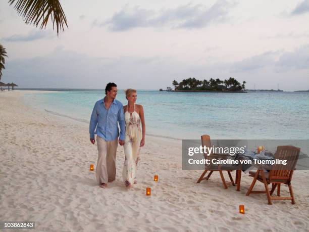 young couple walking on resort beach at sunset - table romantique photos et images de collection