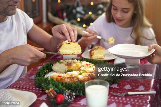 family sitting at the table, father serving slices of a roscón de reyes - roscon de reyes stock pictures, royalty-free photos & images