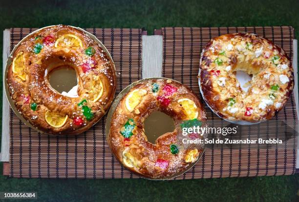 three roscón de reyes decorated with fruits and almonds seen from above - rosca de reyes fotografías e imágenes de stock
