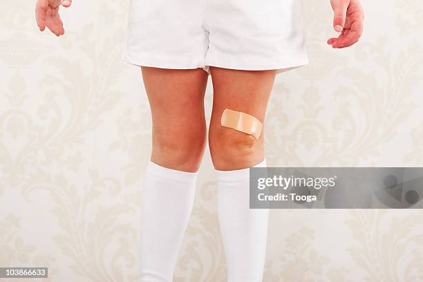 little girls legs with band-aid on knee - scraped knees stock pictures, royalty-free photos & images