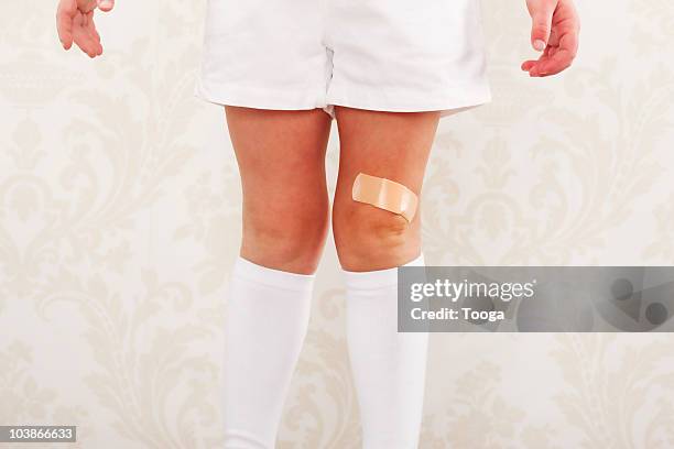 little girls legs with band-aid on knee - scraped knee stock pictures, royalty-free photos & images