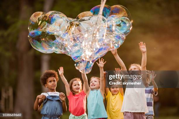 happy kids and heart shaped rainbow bubbles! - enlarged heart stock pictures, royalty-free photos & images