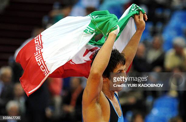 Hamid Soryan of Iran carries a national flag as he celebrates his victory over Gyu-Jin Choi of Korea during their 55 kg Greco-Roman final at the...